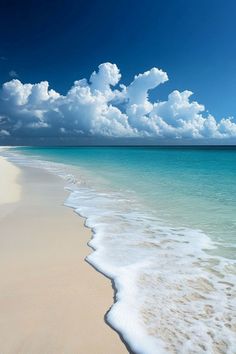 an ocean beach with waves coming in to the shore and blue skies above it on a sunny day