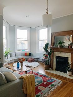 a living room filled with furniture and a fire place in front of two large windows