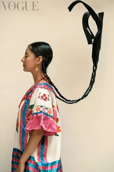 a woman with braids in her hair wearing a colorful dress and carrying a bag