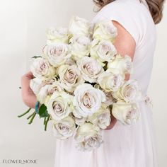 a woman holding a bouquet of white roses