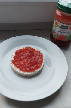 a small piece of food on a plate next to a jar of ketchup