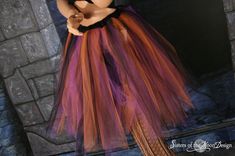 a mannequin dressed in an orange and purple tutu skirt with black trim