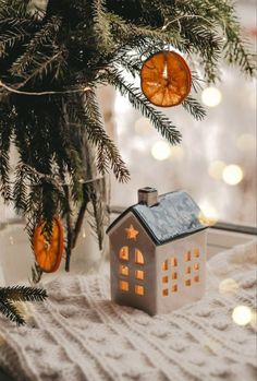 a small house ornament sitting next to a christmas tree