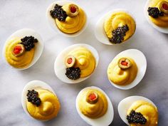 several deviled eggs decorated to look like teddy bears with blackberries in the middle