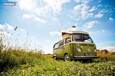 an old vw bus is parked in the middle of a field with tall grass