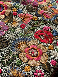 an embroidered fabric with colorful flowers and leaves on black background, closeup view from the neck down