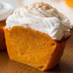 a piece of pumpkin pie with whipped cream on top sitting on a wooden cutting board