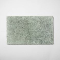 a light green bath rug on a white wall with no one in the room to see it