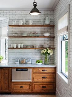 a kitchen with white brick walls and wooden cabinets, open shelving above the stove