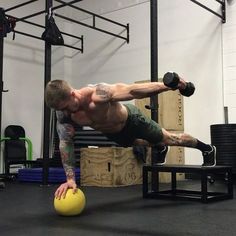 a man doing push ups on a yellow ball in a crossfit gym area