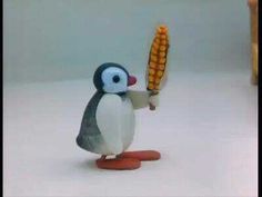 a toy penguin holding an ear of corn