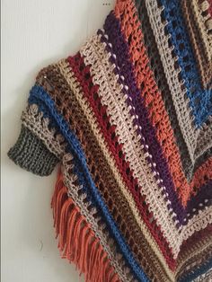 a multicolored crocheted shawl with fringes on the bottom and sides