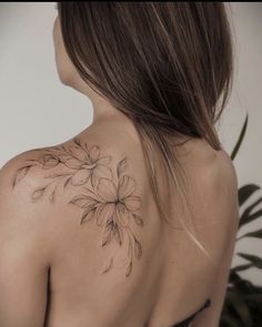 the back of a woman's shoulder with flowers tattooed on her left arm and chest