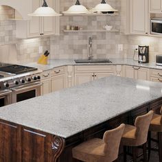 a large kitchen with an island in the middle and several stools at the end