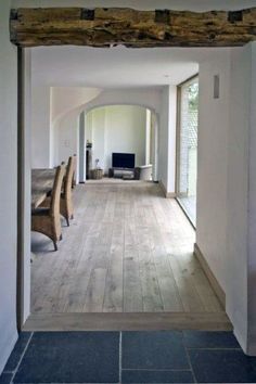 an empty living room and dining area with wood beams on the ceiling, along with tile flooring