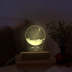 a night light with the moon and stars on it, sitting next to some books