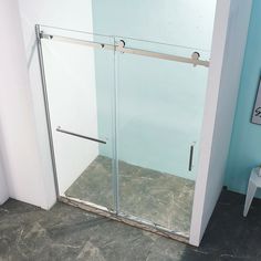 a glass shower door in a bathroom next to a white chair and wall with blue walls