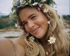 a woman with flowers in her hair smiles at the camera while wearing a flower crown