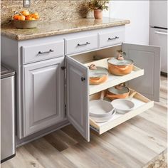 an open cabinet in a kitchen with pots and pans on the bottom shelf,