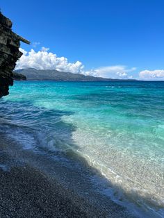 the beach is clear and blue with waves coming in from the water's edge