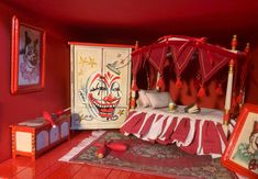 a red room with a bed, dresser and pictures on the wall next to it