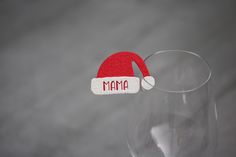 a red santa hat on top of a wine glass with the word mama in it