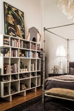 a bed room with a neatly made bed and a book shelf filled with books next to a lamp