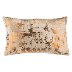 an orange and white pillow with gold paint on the front, sitting on a white surface