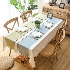 a dining room table with plates and place settings on it in front of a potted plant