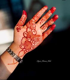 a woman's hand with henna tattoos on her arm and hands, all painted red