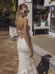 a woman in a white wedding dress is walking down the street with her back to the camera