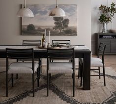 a dining room table with four chairs and a painting on the wall behind it,