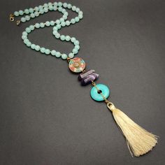 Long aqua blue Tibetan mala necklace with amethyst and howlite turquoise.Wear this unique one of a kind mala necklace and add a bit of boho to your outfit. The focal unit of this mala is made up of a gorgeous large antique style solid brass Tibetan bead, beautiful faceted amethyst pointer style cylindrical beads, a large turquoise howlite donut pendant, numerous aqua/ sky blue round agate beads and a silky tassel.Length: 28"pendant unit length: 7"Agate: It cleanses and stabilizes the aura, elimi Handmade Tassel Necklace As Gift, Handmade Long Tassel Necklace Gift, Adjustable Turquoise Tassel Necklace For Gift, Handmade Spiritual Tassel Necklace For Beach, Bohemian Dangle Tassel Necklace Gift, Bohemian Dangle Tassel Necklace, Bohemian Turquoise Crystal Necklace Gift, Bohemian Tassel Dangle Necklace, Handmade Turquoise Beaded Necklaces For Meditation