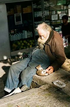 a man sitting on a bench with a cat in his lap