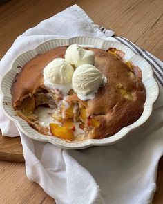 a pie with ice cream and peaches in it on a white plate sitting on a wooden table