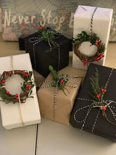 four presents wrapped in black and white paper, tied with twine and decorated with holly wreaths