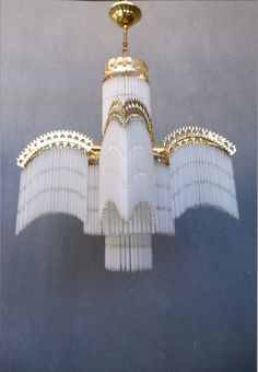 a white chandelier hanging from a ceiling with gold trimmings on it