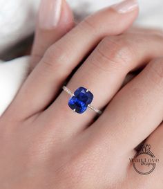 a woman's hand with a blue ring on her finger and a diamond in the middle