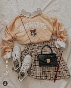 a sweater, skirt, purse and shoes are laid out on a white bed sheet