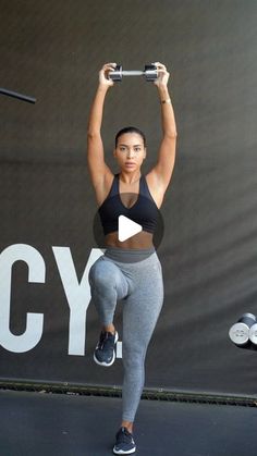 a woman holding a barbell in front of her head and lifting it with both hands