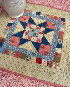 a coffee mug sitting on top of a table next to a quilt