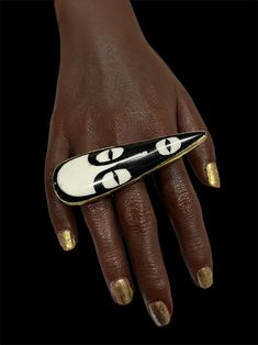 a woman's hand with gold and white nail polish holding a black and white object