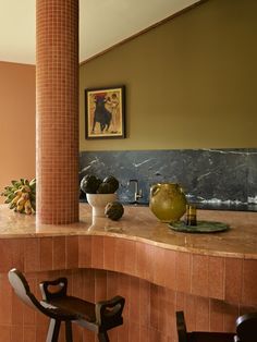 two stools sit in front of a counter with bowls and vases on it