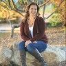 a woman sitting on top of a rock next to a tree