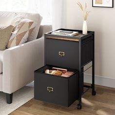 two black storage boxes sitting on top of a wooden floor next to a white couch