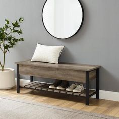 a wooden bench sitting in front of a round mirror on the wall next to a potted plant