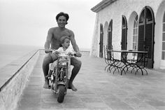 a man riding on the back of a motorcycle next to a little boy sitting on top of it