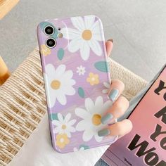 a woman holding up her phone case with flowers on it