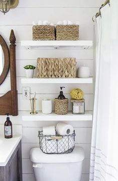 a white toilet sitting in a bathroom next to a wooden shelf filled with baskets and towels