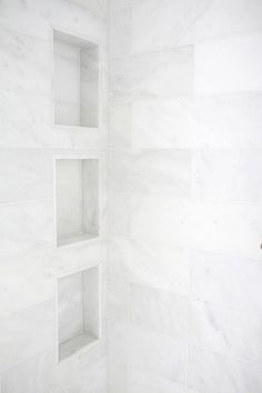 a white tiled shower with shelves on the wall